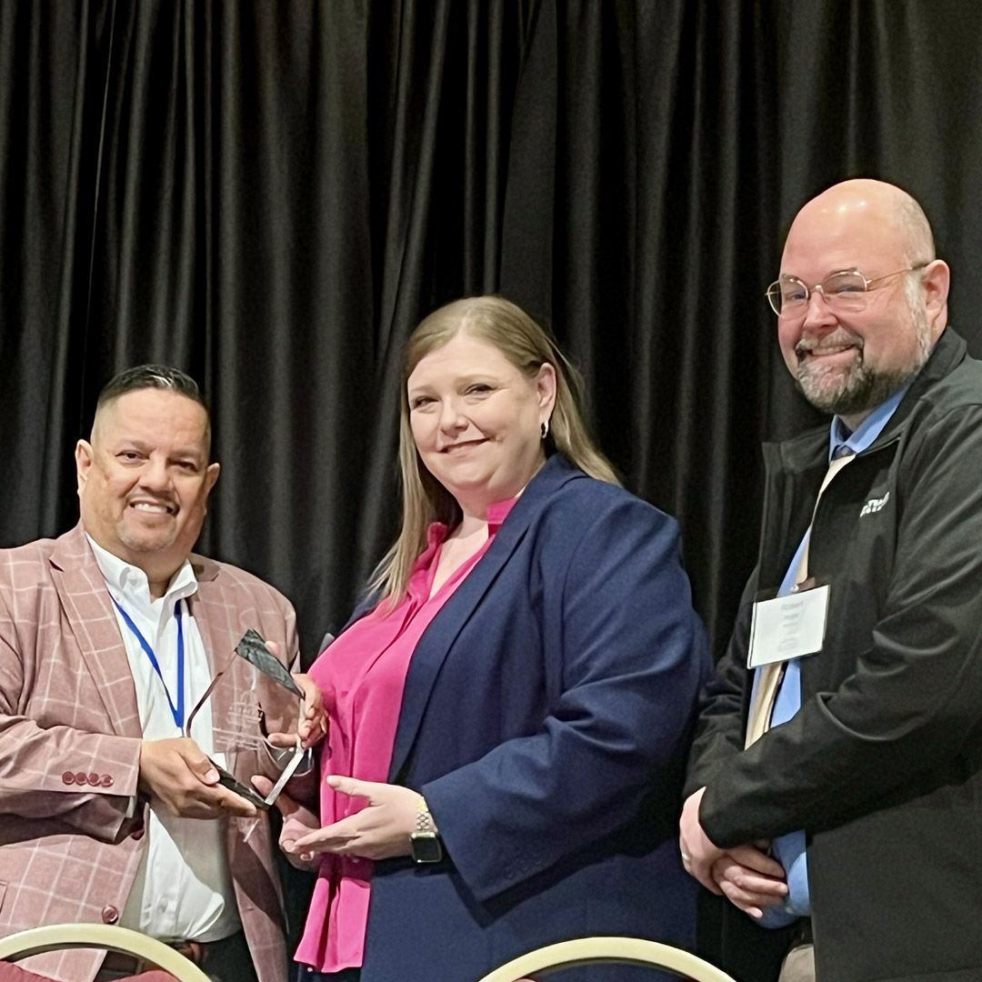 Illinois Department of Commerce and Economic Opportunity Deputy Director Julio Rodriguez presents Man-Tra-Con CEO Stephanie Robinson with the "Excellence in Collaboration Award."
